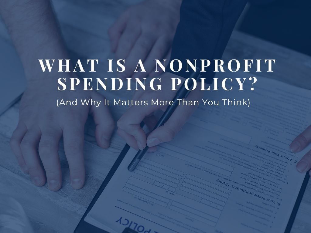 Title of Post: What is a Nonprofit Spending Policy? Overlayed hands holding a pen and reviewing documents. 